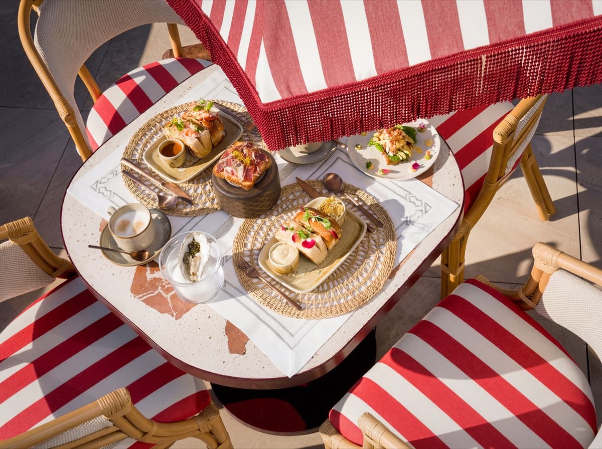 Mesa con platos y bebidas sobre mantel de rayas rojas y blancas.
